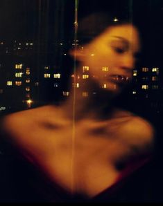 a blurry photo of a woman in front of a cityscape at night