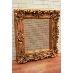 an ornate gold framed mirror sitting on top of a wooden table next to a brick wall