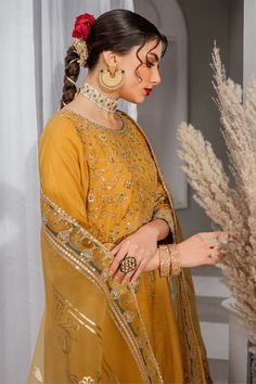 Luxury Mustard Yellow Pakistani Embroidered Salwar Kameez is a simplistic outfit in a mustard shade is crafted on raw silk. The artfully composed neckline, sleeves and hem features, golden embellishments, contrasting color embroidery and lace and tassel detailing, Embroidered Kameez: The beautiful Salwar Kameez comes in a beautiful mustard color and is emblazoned with intricate designs and fine details of embroidery. Floral designs, motifs, and hand-crafted details of sequins, stones, and tilla Gold Anarkali Set, Gold Anarkali Salwar Kameez, Elegant Yellow Dola Silk Anarkali Set, Designer Wear Gold Embroidered Kurta For Navratri, Designer Gold Embroidered Kurta For Navratri, Designer Navratri Kurta With Gold Embroidery, Anarkali Kurta With Gold Embroidery For Transitional Season, Navratri Designer Kurta With Gold Embroidery, Yellow Semi-stitched Raw Silk Kurta