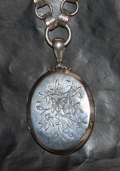 This is an antique sterling silver locket with a floral decoration engraved to the front and a plain back. It's fully hallmarked to the front and partial marks on the back half and on the bail. The chain has no maker's marks that we could find and is most likely not original to the locket.  Condition very good except for an odd blemish to the front which has leached to the inside. Possibly the result of an acid test.  All sales are final, please be sure when you buy; please view all pics for siz Antique Silver Engraved Locket Necklace For Memorial, Engraved Antique Silver Locket Necklace For Memorial, Vintage Sterling Silver Engraved Locket Necklace, Vintage Engraved Sterling Silver Locket Necklace, Collectible Hallmarked Silver Locket Necklace, Ornate Engraved Antique Silver Locket Necklace, Victorian Silver Locket Necklace, Silver Hallmarked Locket Necklace Collectible, Antique Silver Hallmarked Locket Necklace