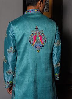 Features a blue silk long jacket embroidered with resham work teamed with a raw silk embroidered Kurta and white cotton chinos Buy the matching set for your partner here. Composition: Kurta and Bundi - Silk , Chinos - Cotton All products can be customised for sleeves, length of blouse and neck design Delivery : 4-6 weeks as the product is hand crafted. Check Size Guide or choose MySize for free customisation (All Sizes above XL can be made at 15% additional cost) For more information and sizes please contact fabiliciousfashion@gmail.com or visit our Copenhagen studio. Silk Sherwani With Embroidery For Reception, Raw Silk Unstitched Suit With Long Sleeves For Reception, Reception Raw Silk Unstitched Suit With Long Sleeves, Fitted Bandhgala With Embroidered Border For Festivals, Embroidered Nehru Jacket With Traditional Drape For Spring, Nehru Jacket With Embroidery And Traditional Drape For Spring, Fitted Nehru Jacket With Embroidered Border For Festivals, Fitted Sherwani With Embroidered Border For Transitional Season, Spring Cotton Bandhgala With Resham Embroidery