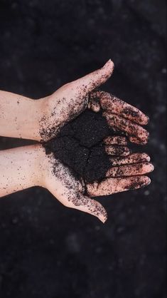 a person's hand with dirt on it and black ground in the background,