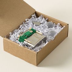 an open cardboard box with a lighter and other items in it on a white surface