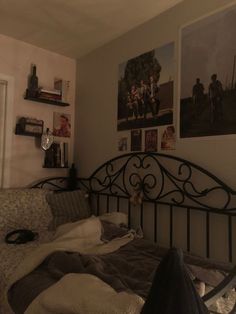 an unmade bed with pictures on the wall above it