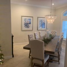 the dining room table is set with white chairs and christmas trees in front of it