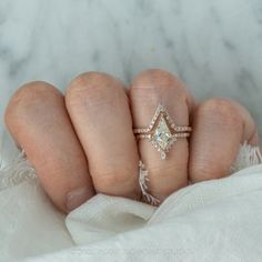 a woman's hand with three different rings on her fingers and one diamond ring in the middle