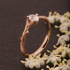 a close up of a gold ring with flowers in the foreground and white flowers on the background