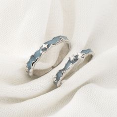 two silver rings sitting on top of a white cloth