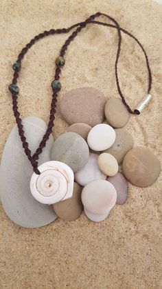 a necklace with various stones and beads laying on the sand