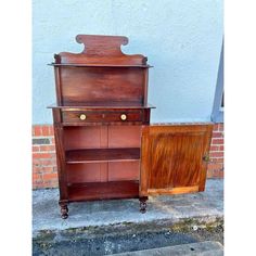 an old wooden cabinet sitting next to a brick wall on the side of a street