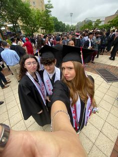 two girls in graduation caps and gowns pointing at the camera