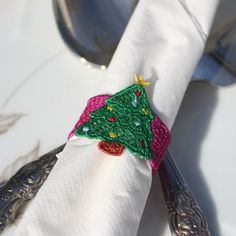 a white napkin with a christmas tree on it and silverware next to the napkin