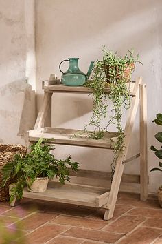 a wooden shelf with potted plants next to it on a tile floor in front of a white wall