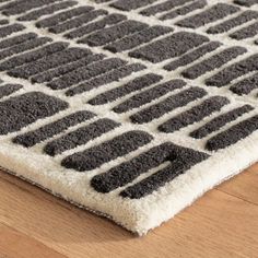 a close up of a rug on a wooden floor with black and white designs in the middle