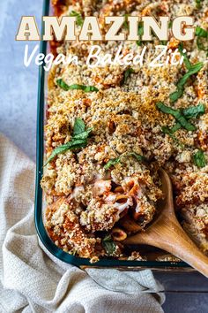 a casserole dish filled with vegetables and topped with breadcrumbs on a wooden spoon