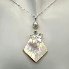 This yellow mother of pearl diamond shaped pendant has gorgeous tones of pinks, purples and light greens. Sadly it is the only one I have. It is topped with a carved mother of pearl plumeria with a small Swarovski yellow crystal in the center. A lustrous oval freshwater pearl tops this pendant. It is about 2 1/4 inches from the top of the sterling silver wire wrap to the bottom of the pendant. The necklace can come in many lengths. If you don't see a length you need please message me. To see mor Pearl White Mother Of Pearl Shell Necklace Gift, Pearl White Mother Of Pearl Shell Necklace As Gift, White Mother Of Pearl Pendant Shell Necklace, Unique Mother Of Pearl Jewelry With Pearl Pendant, Unique Mother Of Pearl Shell Necklace Gift, Shell-shaped Mother Of Pearl For Jewelry Making, Elegant Mother Of Pearl Shell Pendant Necklace, Artisan Shell-shaped Mother Of Pearl Jewelry, Artisan Mother Of Pearl Shell Jewelry