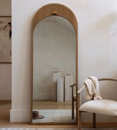 a mirror sitting on top of a wooden floor next to a chair