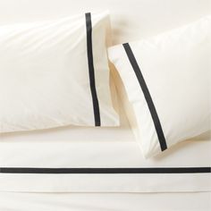 two white and black pillows on top of a bed next to each other with matching sheets