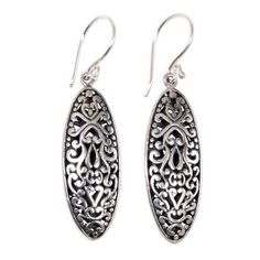 Inspired by traditional Balinese designs Komang Suastra hand crafts this lovely pair of earrings. These unique oval shpaed sterling silver earrings feature an intricately engraved floral motif accented by an oxidized finish. Ornate Oval Sterling Silver Earrings, Oval Earrings With Intricate Design For Anniversary, Traditional Sterling Silver Engraved Earrings, Traditional Engraved Sterling Silver Earrings, Ornate Engraved Sterling Silver Earrings, Traditional Oval Filigree Earrings, Traditional Engraved Teardrop Earrings, Filigree Oval Earrings As Gift, Ornate Oval Pierced Earrings