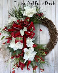 a christmas wreath with white flowers and red ribbon hanging on a wooden wall next to the words, the kraffed front porch