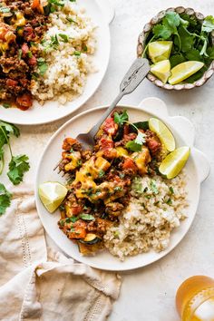 two plates filled with rice, meat and vegetables next to a glass of orange juice