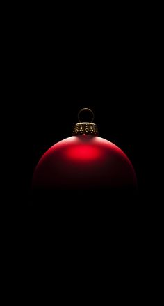 a red ornament on a black background with the light reflecting off it's side