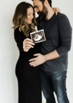 a man and woman standing next to each other while holding an object in their hands