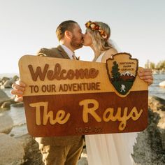 a bride and groom kiss while holding a welcome sign for their adventure destination the rays