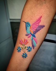 a colorful hummingbird with flowers on the left arm and back of the arm is shown