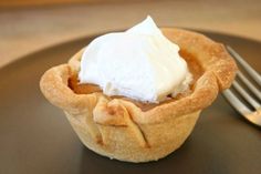 there is a small pie with whipped cream on top and a fork next to it