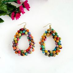 two pairs of colorful beaded earrings next to flowers