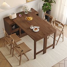 a wooden table with chairs around it and plates of food on the table next to it