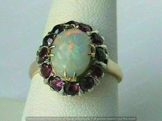 an opalite ring is shown on top of a white cloth with red and purple stones