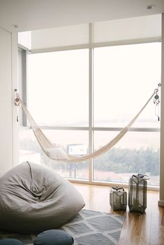 a hammock hanging from the side of a window next to a bed with pillows on it