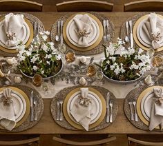 the table is set with white and gold plates, silverware, and napkins