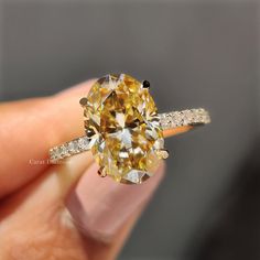 a close up of a person's hand holding a fancy ring with an orange diamond