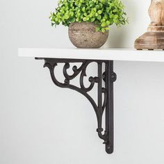 a potted plant sitting on top of a white shelf next to a wooden statue