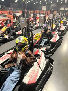 a row of go - karts lined up in an indoor area with people sitting on them