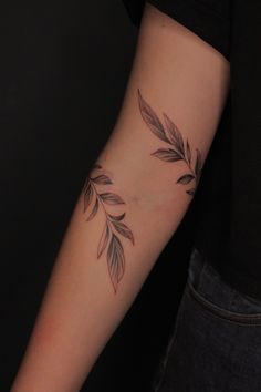 a woman's arm with a tattoo on it that has leaves coming out of it