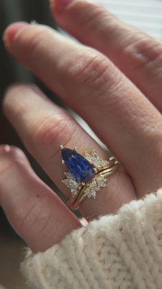 a woman's hand with a ring on it and a blue stone in the middle