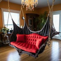 a red couch hanging from a chandelier in a living room