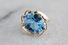 This vintage gold mounting is simple with decorative, sweeping shoulders on the sides and secure prongs. This piece is set with a modern, blue topaz. The color of this stone is deeper, a rich, almost turquoise water color. This would make a lovely cocktail ring, and is also a sturdy enough stone to wear everyday! Metal: 10K Yellow Gold Gem: Blue Topaz 4.46 Carats Gem Measurements: 11.9 x 9.8 mm, Oval Ring Size: 4.25 Classic Topaz Ring With Gemstone Accents, Timeless Oval Blue Topaz Ring, Timeless Blue Oval Topaz Ring, Elegant Blue Topaz Ring In 14k Gold, Classic Blue Topaz Solitaire Ring, Vintage Blue Topaz Ring In 14k Gold, Elegant Turquoise Blue Topaz Ring, Blue Topaz Solitaire Ring For Formal Occasions, Formal Blue Topaz Solitaire Ring