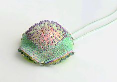 a hair brush with colorful sequins on it sitting on a white surface next to a cord