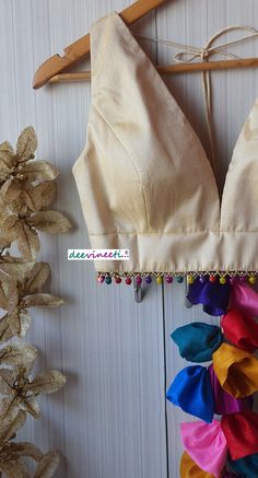 This Made to Order/Made to Measurement/Custom Made Indian Ethnic Blouse. - Fabric - Raw Silk - Color - Cream - Princess Cut - Padded - Plunging Neckline - Back Hook Closure - Dori on the shoulder with Multicolor Fabric Tassels - Sleeveless - Multicolor Ghungroo around the waist Fabric Care : Dry Clean Only Disclaimer: The actual color of the product might slightly differ from the image due to photographic lighting or monitor's display Shipping: This is made to order product. Once you place the o Multicolor V-neck Choli For Festive Occasions, Bohemian V-neck Unstitched Choli, Festive Multicolor V-neck Blouse Piece, Festive Bohemian V-neck Blouse Piece, Traditional Blouse Piece With Latkans For Navratri, Multicolor Choli With Latkans For Diwali, Bollywood Style Blouse Piece With Latkans For Festivals, Multicolor V-neck Blouse Piece For Party, Bollywood Blouse Piece With Latkans For Diwali