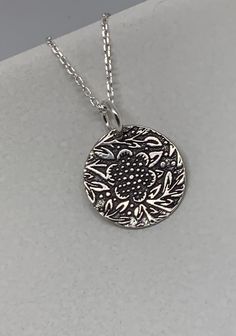 This beautiful floral circle silver necklace pendant has been entirely handmade using .999 fine silver. It has been cut from fine silver precious metal clay, textured, fired and oxidized. The pendant hangs from a sterling silver diamond cut cable chain. This unique and handmade necklace features an embossed floral leaf branch pattern. Pendant size: approximately 1/2 x 1/2 inches Chain length: adjustable at 16 and 18 inches can also be customized to whatever length needed The necklace is sent in Etched Sterling Silver Necklaces, Silver Etched Sterling Silver Necklace, Artisan Silver Etched Necklace, Antique Silver Etched Sterling Silver Necklace, Silver Etched Nature-inspired Necklaces, Bohemian Sterling Silver Jewelry With Flower Charm, Bohemian Sterling Silver Flower Necklace, Nature-inspired Silver Etched Necklaces, Sterling Silver Medallion Necklace With Flower Charm