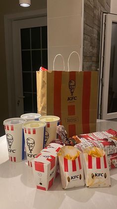 several bags of food sitting on top of a counter next to two cups and a paper bag