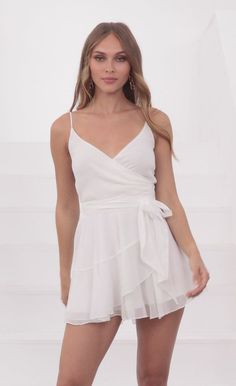 This ruffled wrap dress is about to be your favorite go-to dress for work, vacations and fun evenings out! With soft shimmery fabric, you'll never want to take it off. The wrap around makes for the most flattering fit and easy to slip on whenever you need! Pair with some white sneakers and hoop earrings to make for a comfy and cute ensemble.   Designed in Los Angeles - A-line Silhouette- Ruffled Trimming- Ties on Side- Dress is Sheer Length of Dress Measures 31in/78.74cm.All Measurements Are For Summer Chiffon Wrap Dress With Surplice Neckline, Flirty Wrap Dress, Surplice Neckline Ruffle Wrap Dress For Party, Surplice Neckline Wrap Dress With Ruffles For Party, Party Wrap Dress With Ruffles And Surplice Neckline, Summer Mini Dress With Wrap-around Straps For Date Night, Summer Wrap-around Straps Mini Dress For Date Night, Chic Chiffon Wrap Dress, Flowy Wrap Dress For Date Night