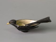 a small black bird sitting on top of a white bowl