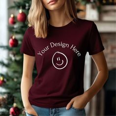 a woman standing in front of a christmas tree wearing a t - shirt that says your design here