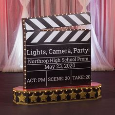 a black and white clapper sign with lights on it in front of a curtain